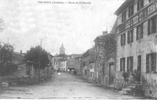 Rue bordée de maisons, clocher au fond
